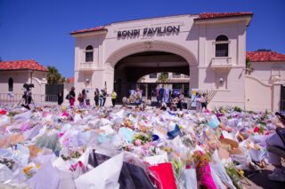 People,Gather,At,A,Flower,Memorial,Outside,The,Bondi,Pavilion